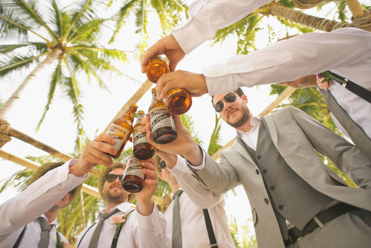 A group of stags cheering beers under a palm tree before going out